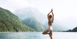 A traveler doing a yoga pose near the water