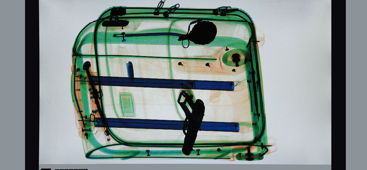 Image: X-ray of a gun inside of a suitcase at the airport. (photo via sspopov/iStock/Getty Images Plus)