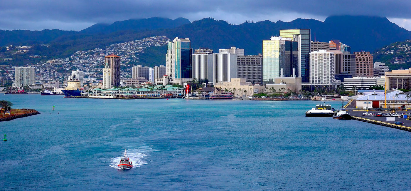 Image: PHOTO: View of downtown Honolulu, Oahu from the deck of a cruise ship as it heads out to sea. (Photo via CrackerClips / iStock / Getty Images Plus)