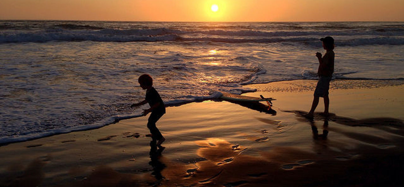 Image: PHOTO: Children frolicking on the beach in sunset. (photo via Flickr/Kevin Krejci)