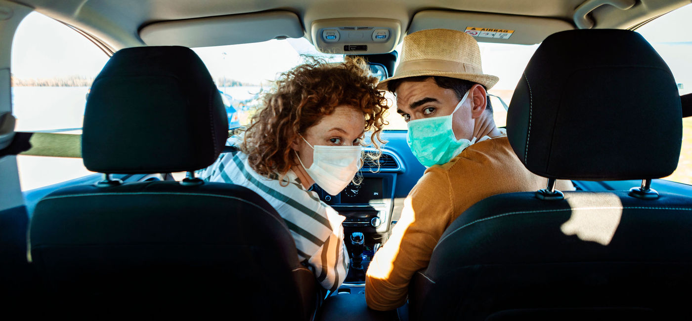 Image: A couple wearing face masks on a road trip. (photo via ljubaphoto/E+)