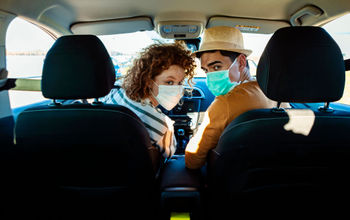 A couple wearing face masks on a road trip