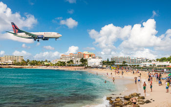 Delta flight approaches St Maarten's Princess Juliana Airport above onlookers on Maho Beach