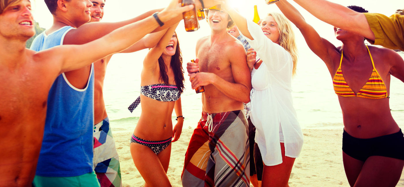 Image: A group of friends celebrating on a tropical beach. (Photo via iStock / Getty Images Plus / Rawpixel)