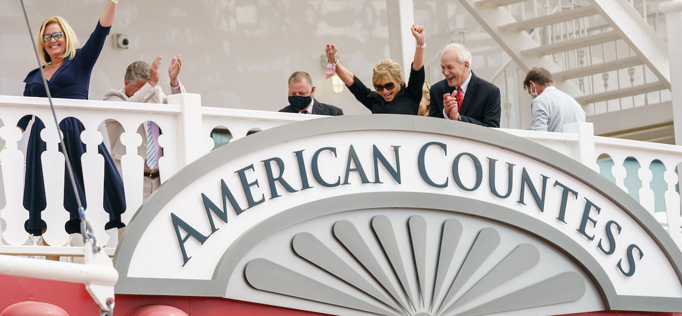 Image: Angie Hack christens American Countess with a bottle of Maker’s Mark bourbon, alongside Claudette Waggoner and John Waggoner. (photo via American Queen Steamboat Company)