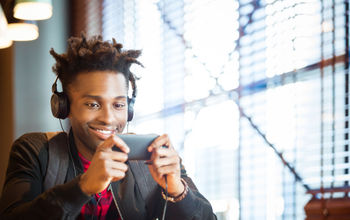 Young man watching a movie on his smartphone at an airport cafe.