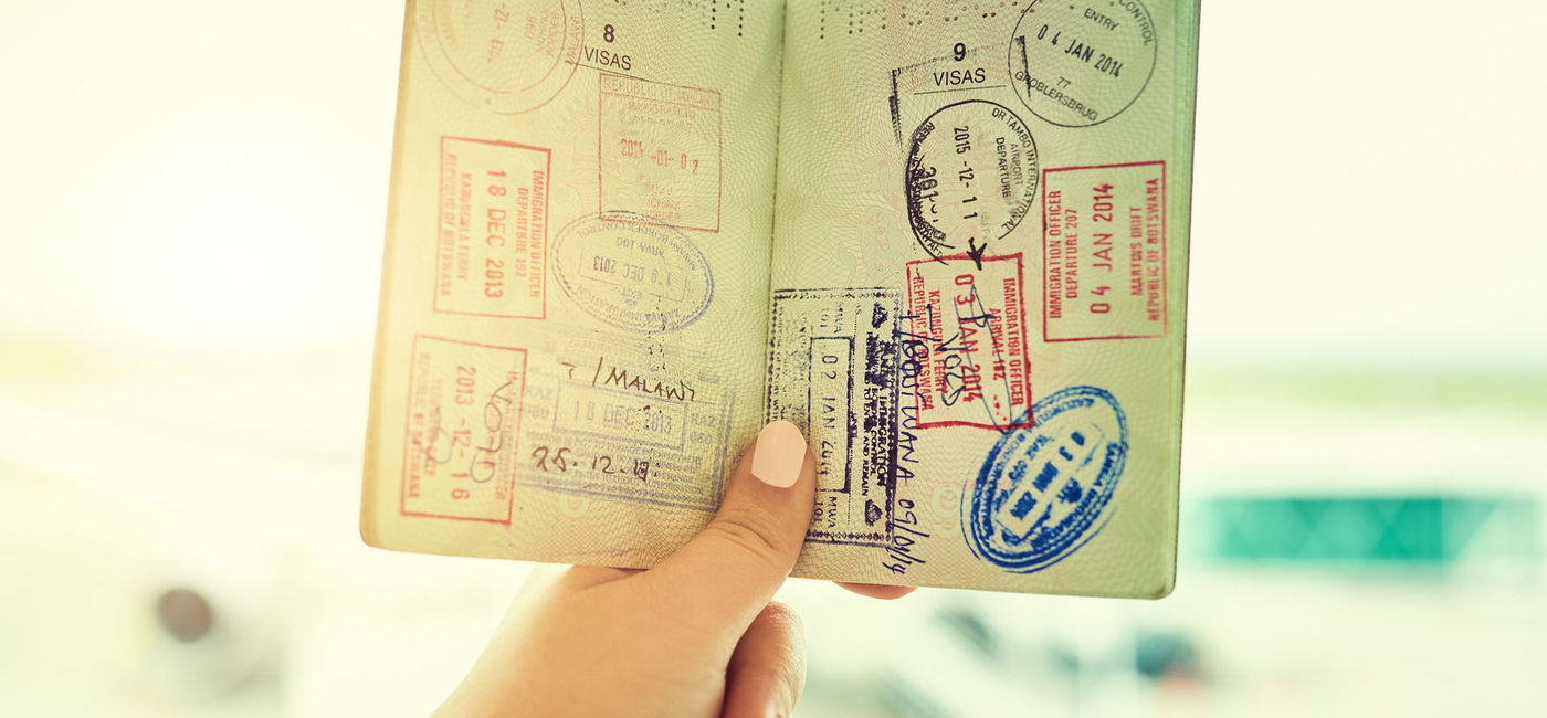 Image: Person holding a passport filled with stamps. (Photo via iStock/Getty Images Plus/PeopleImages)