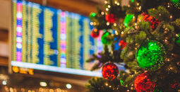 Christmas tree in front of an airport departures board.