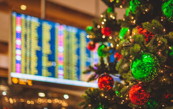 Christmas tree in front of an airport departures board.