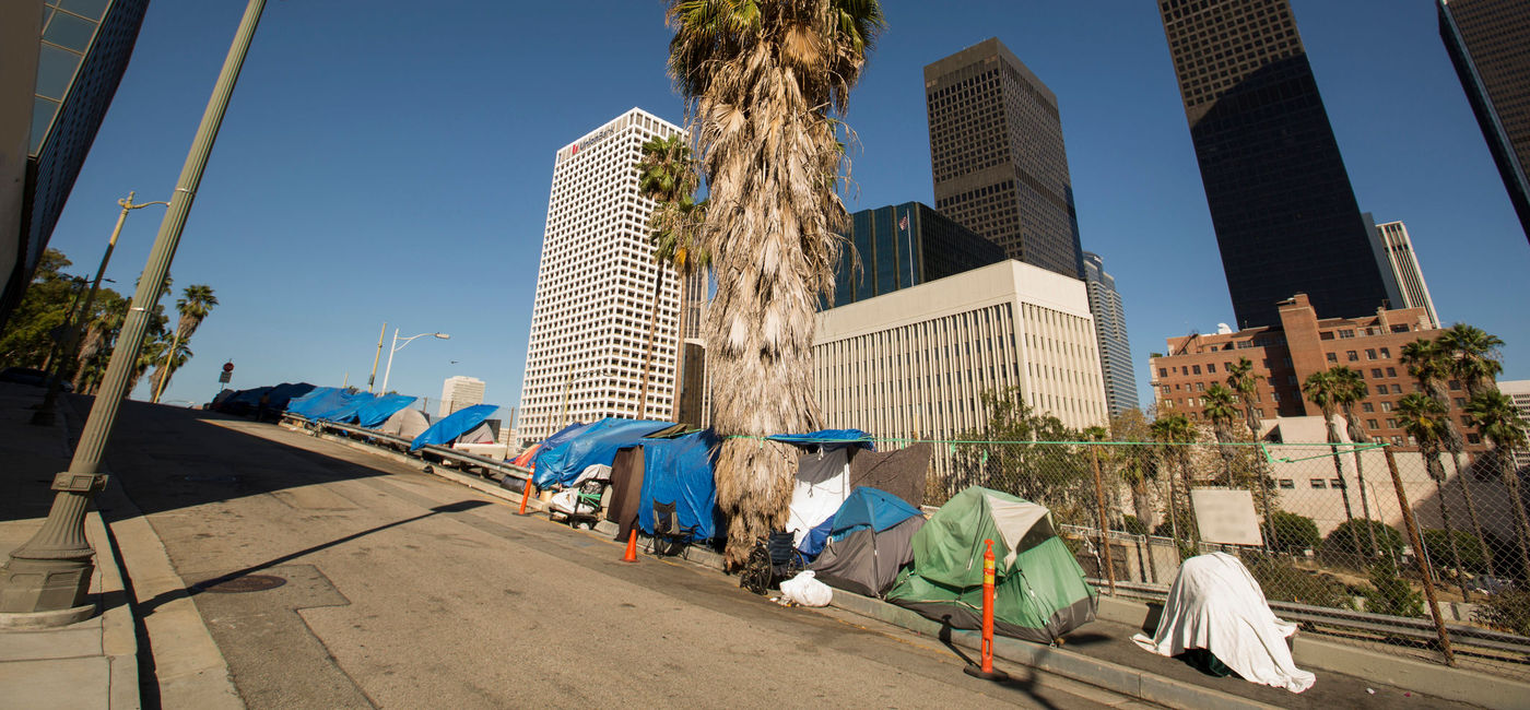 Image: A homeless encampment next to a Downtown Los Angeles freeway. (Photo Credit: MattGush / iStock / Getty Images Plus)