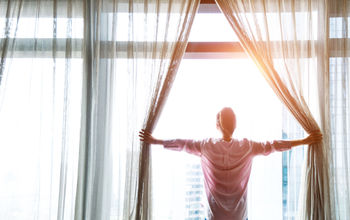 Woman at window with curtains.