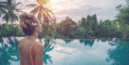 Woman by the edge of an infinity pool enjoying tropical climate in Ubud, Bali.