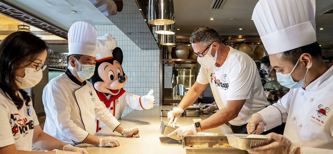 Image: Mickey joins Disney VoluntEARS in the kitchen to create pre-packed meals. (photo courtesy of Disney Parks)