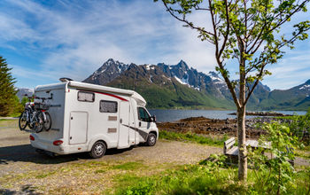 An RV parked beside a mountain lake.