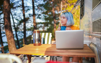 Woman working on her laptop outside an RV.