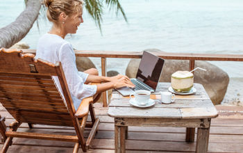 Woman working on a laptop in a tropical destination.