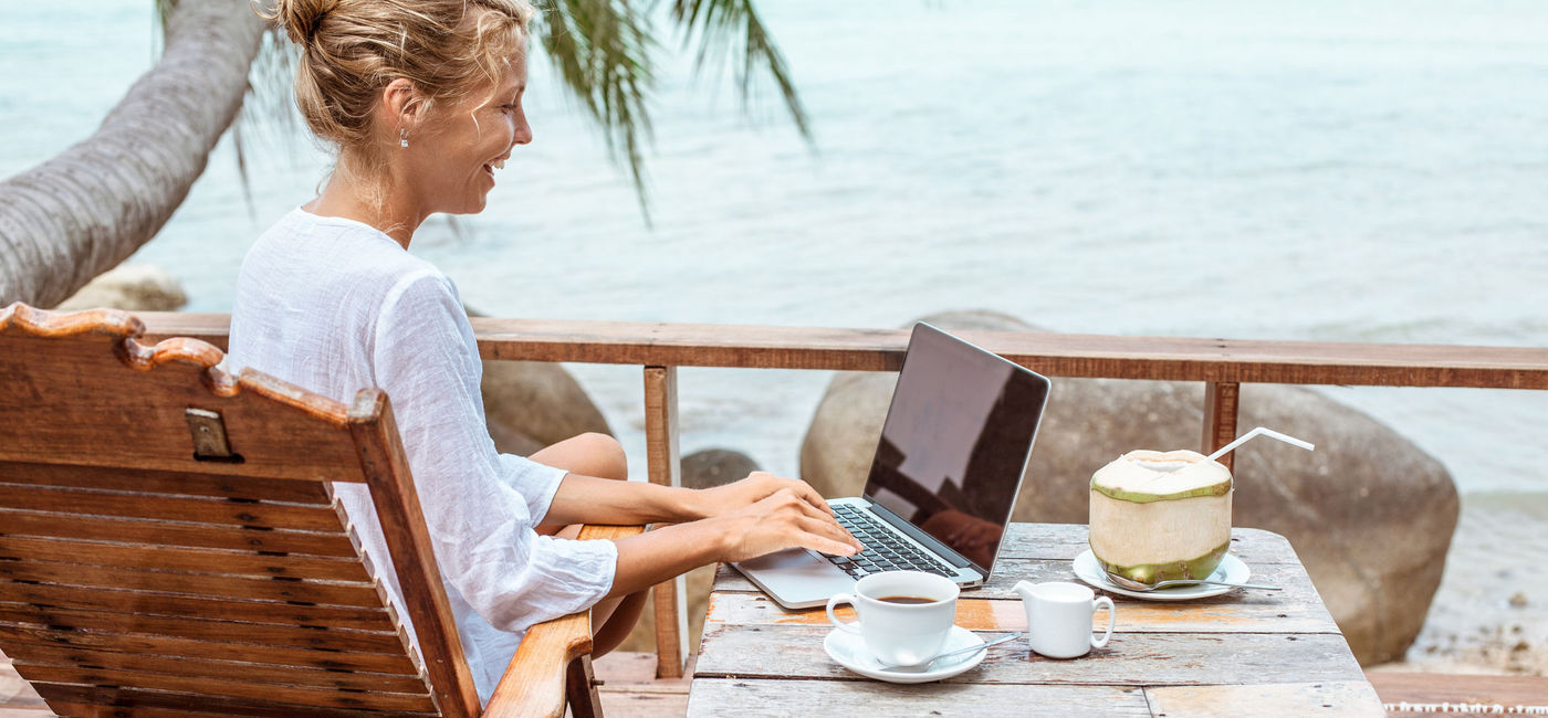 Image: Woman working on a laptop in a tropical destination. (Photo via iStock/Getty Images E+/Jasmina007)