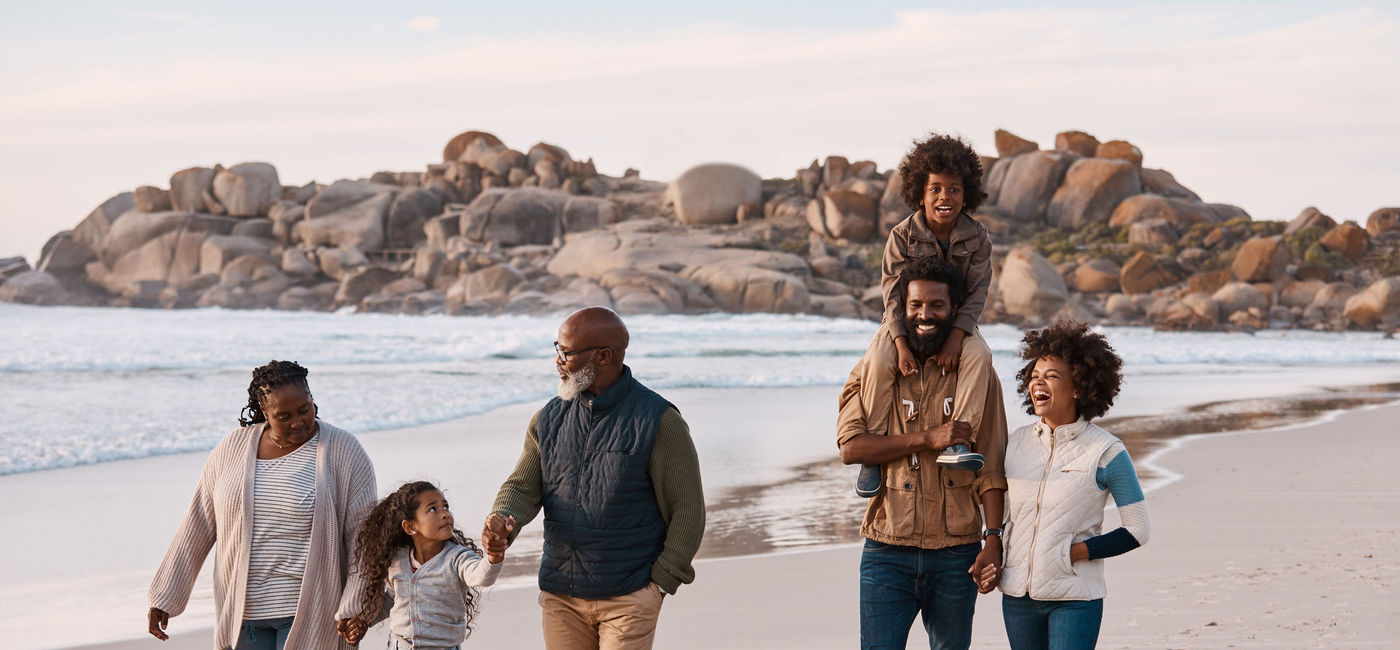 Image: Family walking on the beach. (photo via kupicoo / Getty Images)