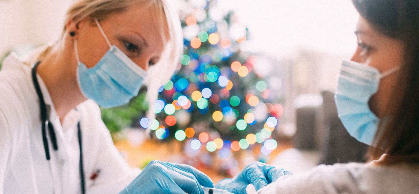 Image: A woman getting vaccinated against COVID-19 prior to holiday travel. (photo via iStock/Getty Images Plus/Pyrosky)
