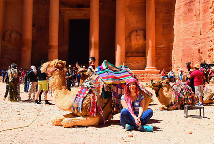 Woman sits with camels outside of the Wonders of the World in Petra, Jordan.