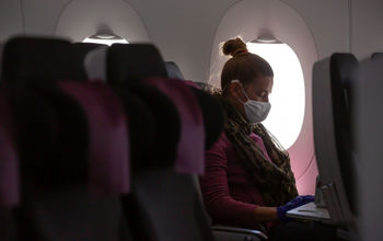 A woman wearing a face mask on an airplane