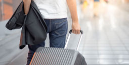 Man holding suit and luggage