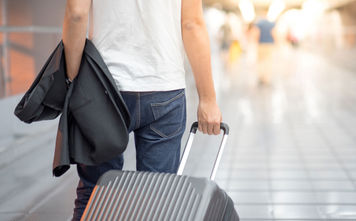 Man holding suit and luggage