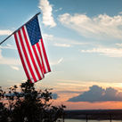 Bright american flag flying above beautiful sunset over Mississippi river