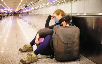 COVID-19, coronavirus, Omicron, masks, luggage, suitcase, airport, concourse, frustrated, sad, irritated, tired, exhausted, traveler, passenger, flier, flyer