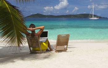 Woman sitting on the beach with her laptop in St. John, US Virgin Islands