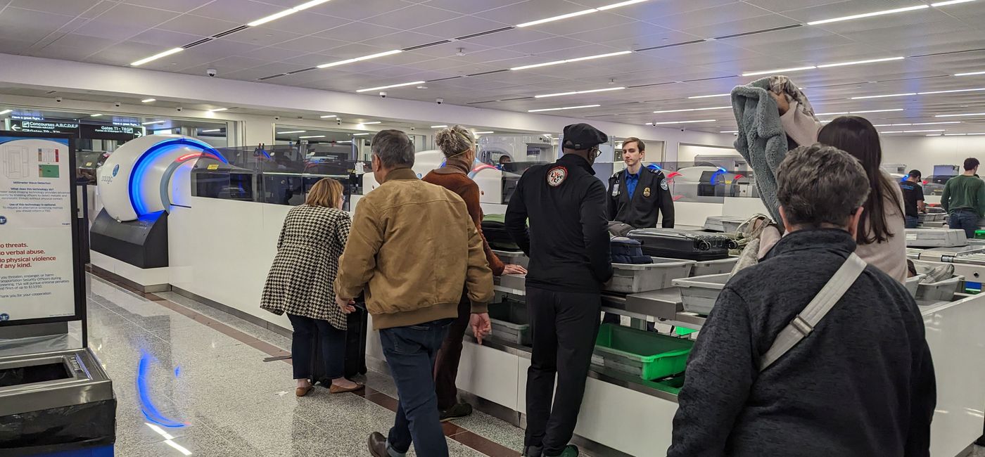 Image: Travelers placing items in bins at TSA security line. (photo by Eric Bowman)