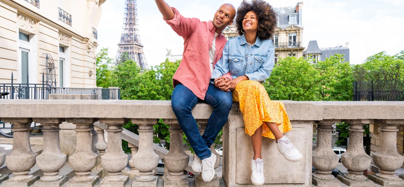Image: A couple takes a photo with the Eiffel Tower in the background. (photo via Air Canada)