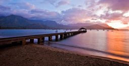 Pier into ocean with sunset behind