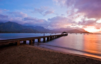 Pier into ocean with sunset behind