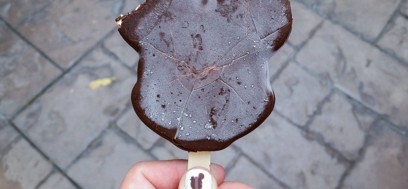 Photo: Enjoying a delicious Mickey Ice Cream Bar while waiting to watch Mickey and the Magical Map in the Fantasyland Theatre. (Photo via HarshLight / flickr)