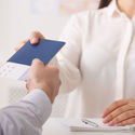 Travel agent giving passport with tickets to tourist