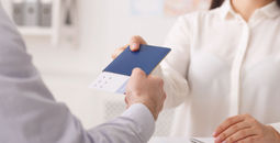 Travel agent giving passport with tickets to tourist