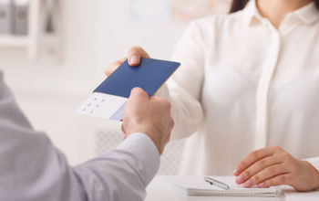 Travel agent giving passport with tickets to tourist