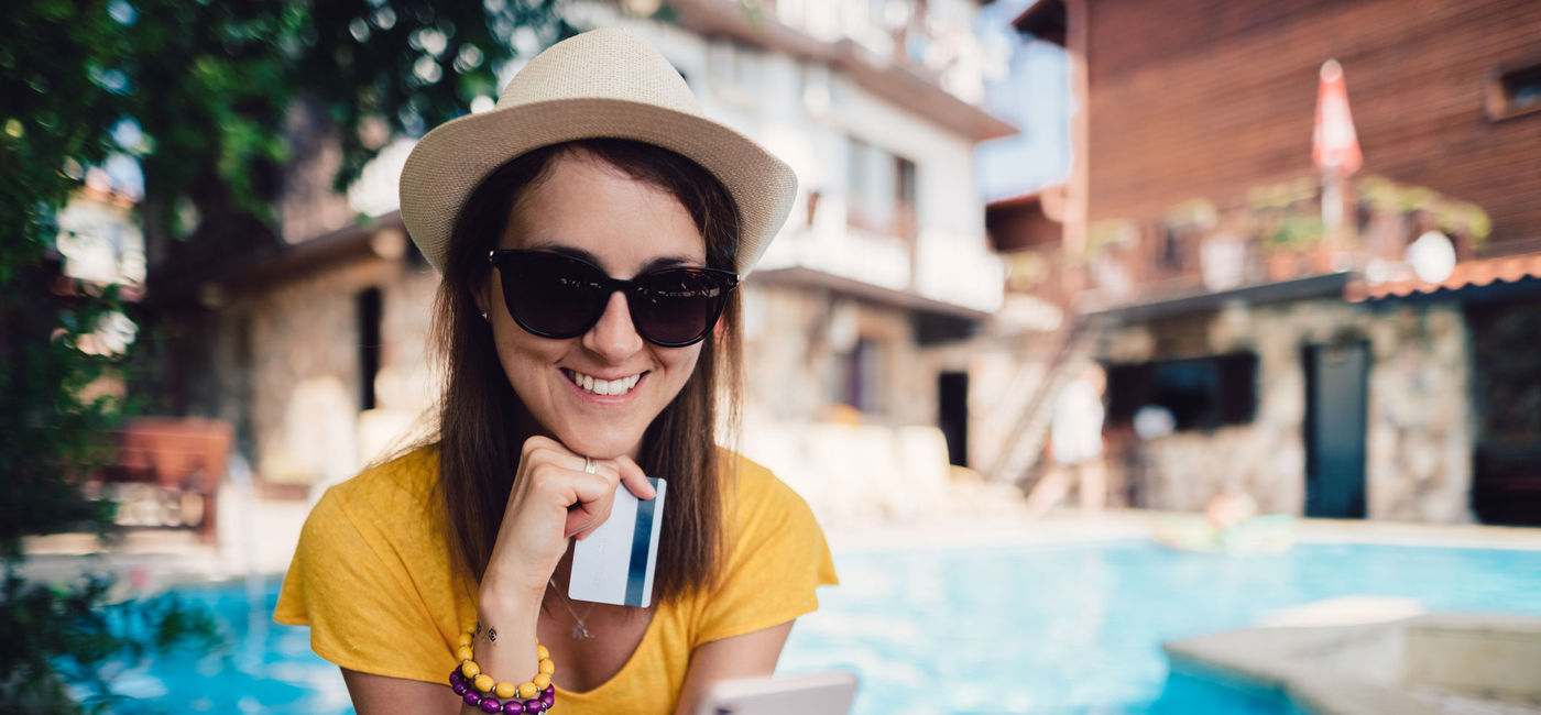Image: Woman booking travel from her phone. (photo via martin-dm/E+)