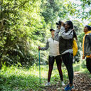Travelers using binoculars in a forest 