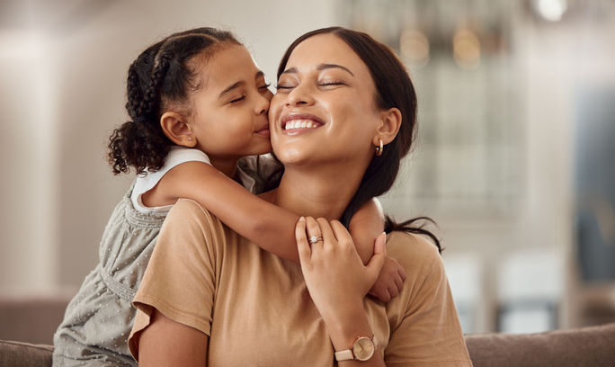 A young girl kisses her mother on the cheek. girls, woman, family, parents, kisses, hugs, embraces, affection, young, children, kids, mother's day, moms, daughters