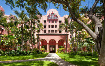 Green courtyard of Royal Hawaiian Hotel with Pink stucco building in background
