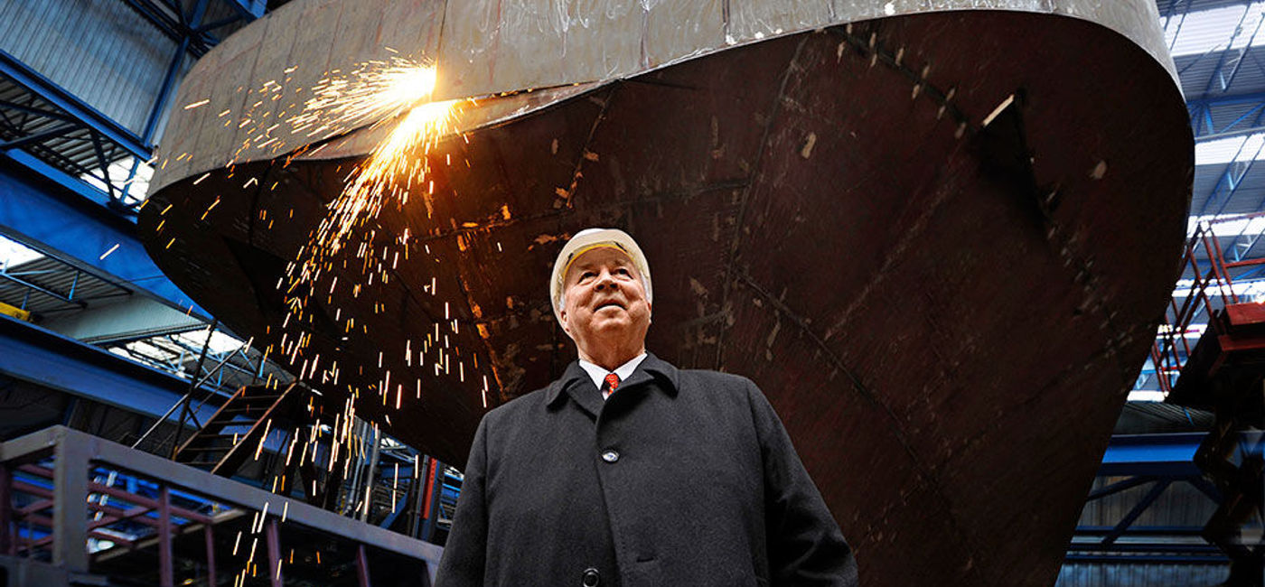 Image: PHOTO: Viking Cruises founder and chairman Torstein Hagen in front of a Viking Longship under construction. (photo courtesy of Viking Cruises)
