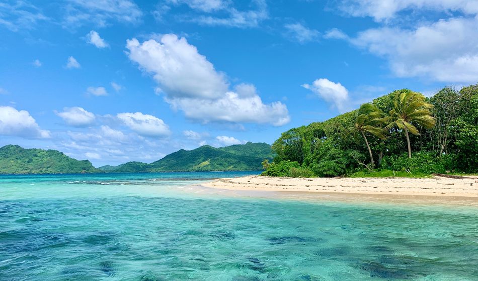 Island with turquoise water, white sand beach, blue sky