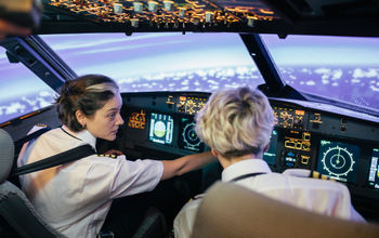 Flight instructor and trainee in a simulator cockpit.