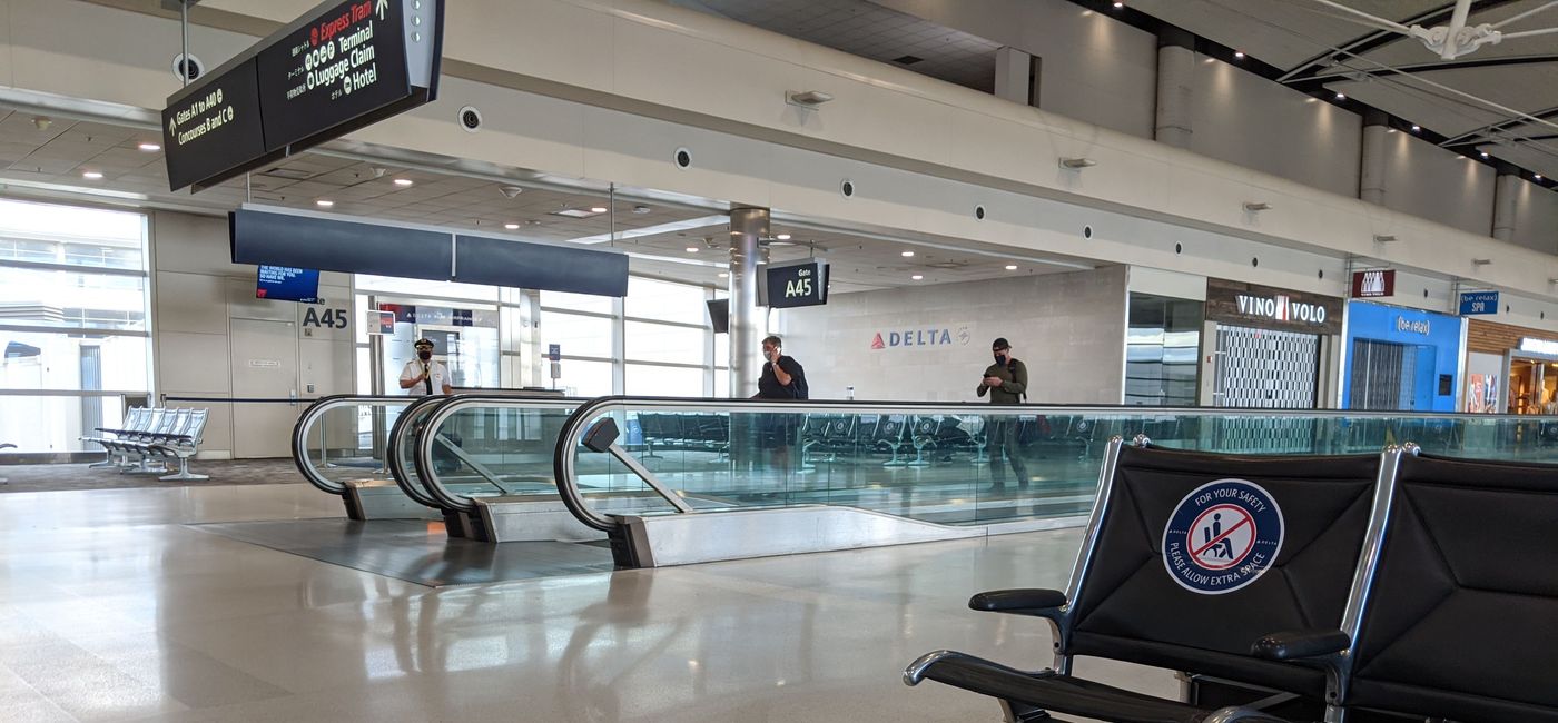 Image: Travelers walking in the airport wearing face masks (photo by Eric Bowman)