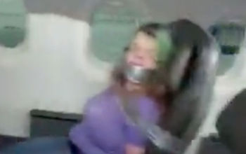 A still from social media footage of an airplane passenger duct-taped to her seat after assaulting crew members.