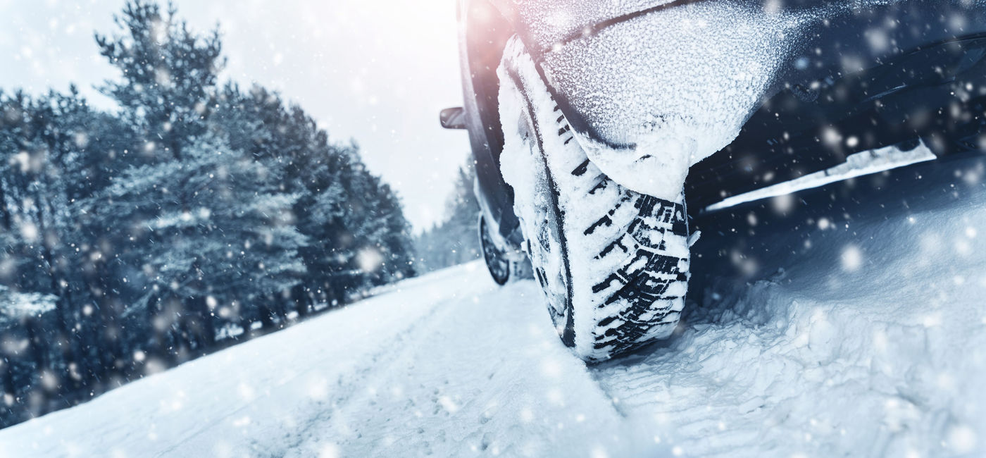 Image: Closeup on tires of a car driving in a snowstorm. (photo via iStock/Getty Images Plus/LeManna)