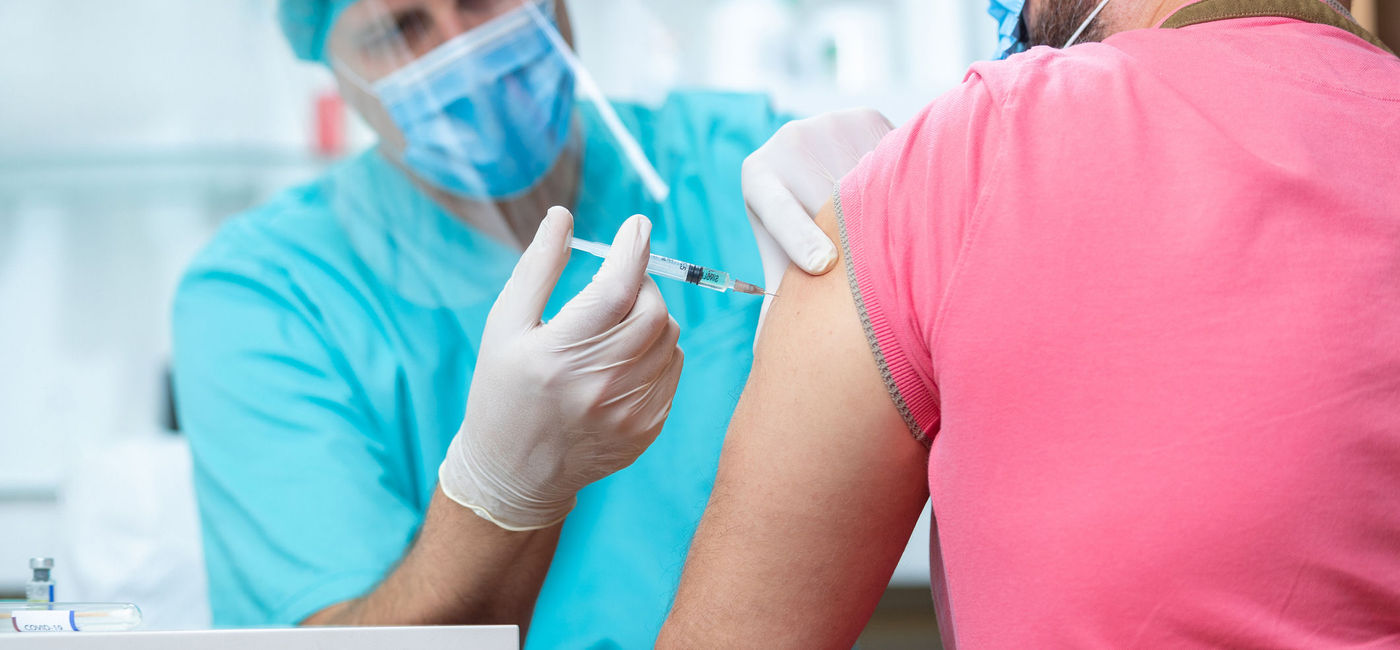 Image: Doctor wearing PPE administering vaccine to a patient. (Photo via iStock/Getty Images Plus/zoranm)