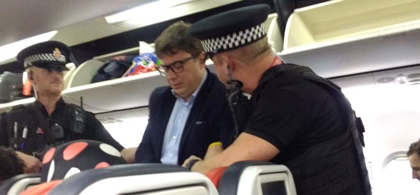 Image: Guy Lardinois being arrested by police after striking a flight attendant.  (Photo via @DailyMirror)
